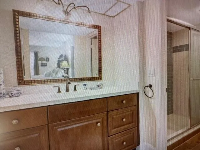 a bathroom with a granite countertop sink vanity mirror and shower