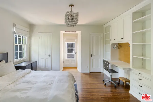a bedroom with a bed and a dresser next to a window