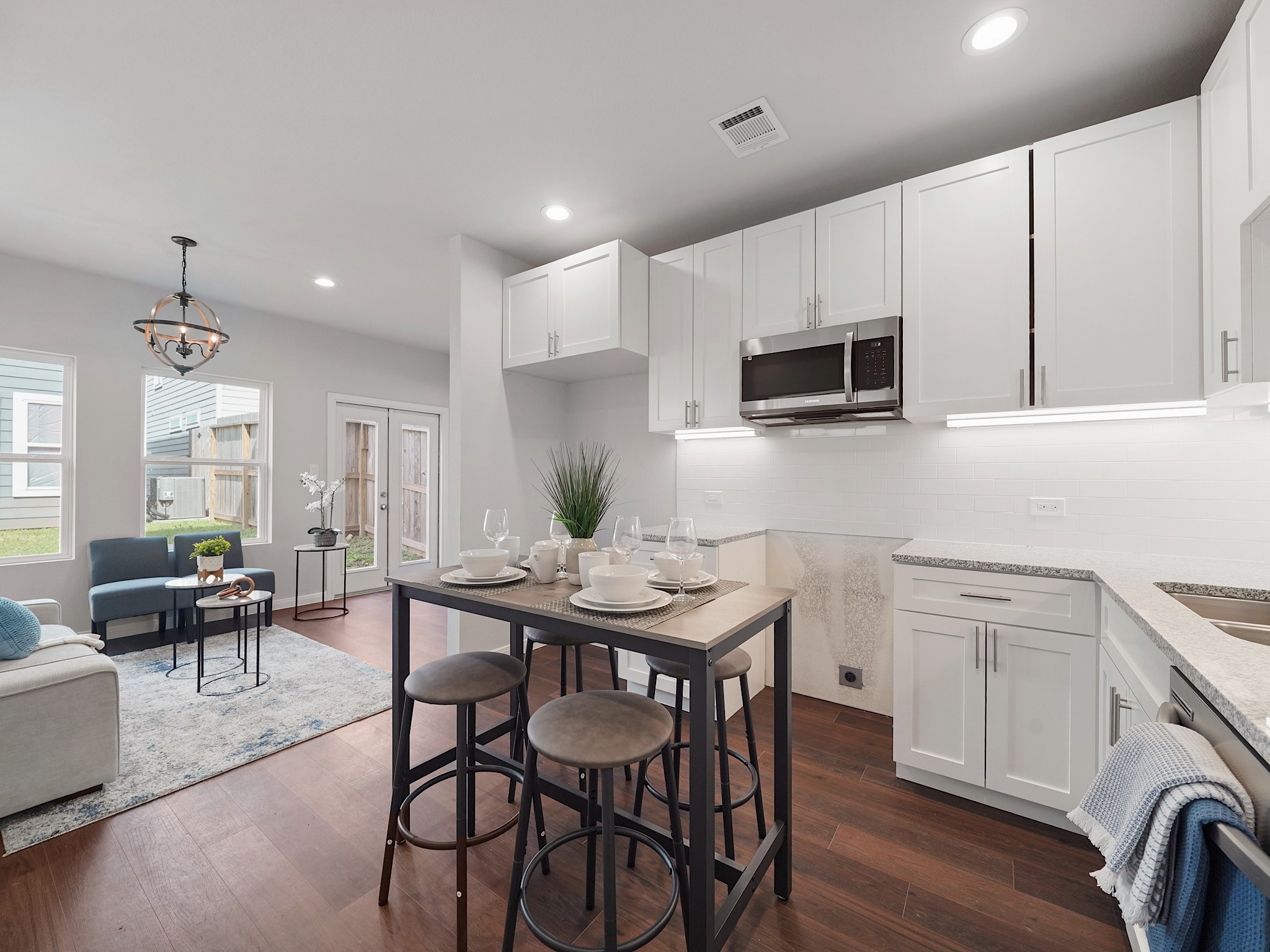 a kitchen with stainless steel appliances kitchen island granite countertop a stove a sink a microwave a dining table and chairs with wooden floor