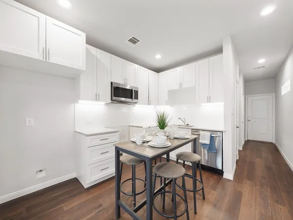 a kitchen with stainless steel appliances kitchen island granite countertop a sink dishwasher a stove a refrigerator with a dining table and chairs