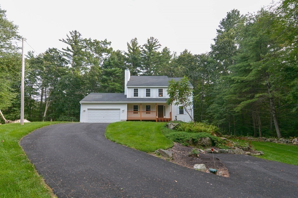 a front view of a house with a garden and trees