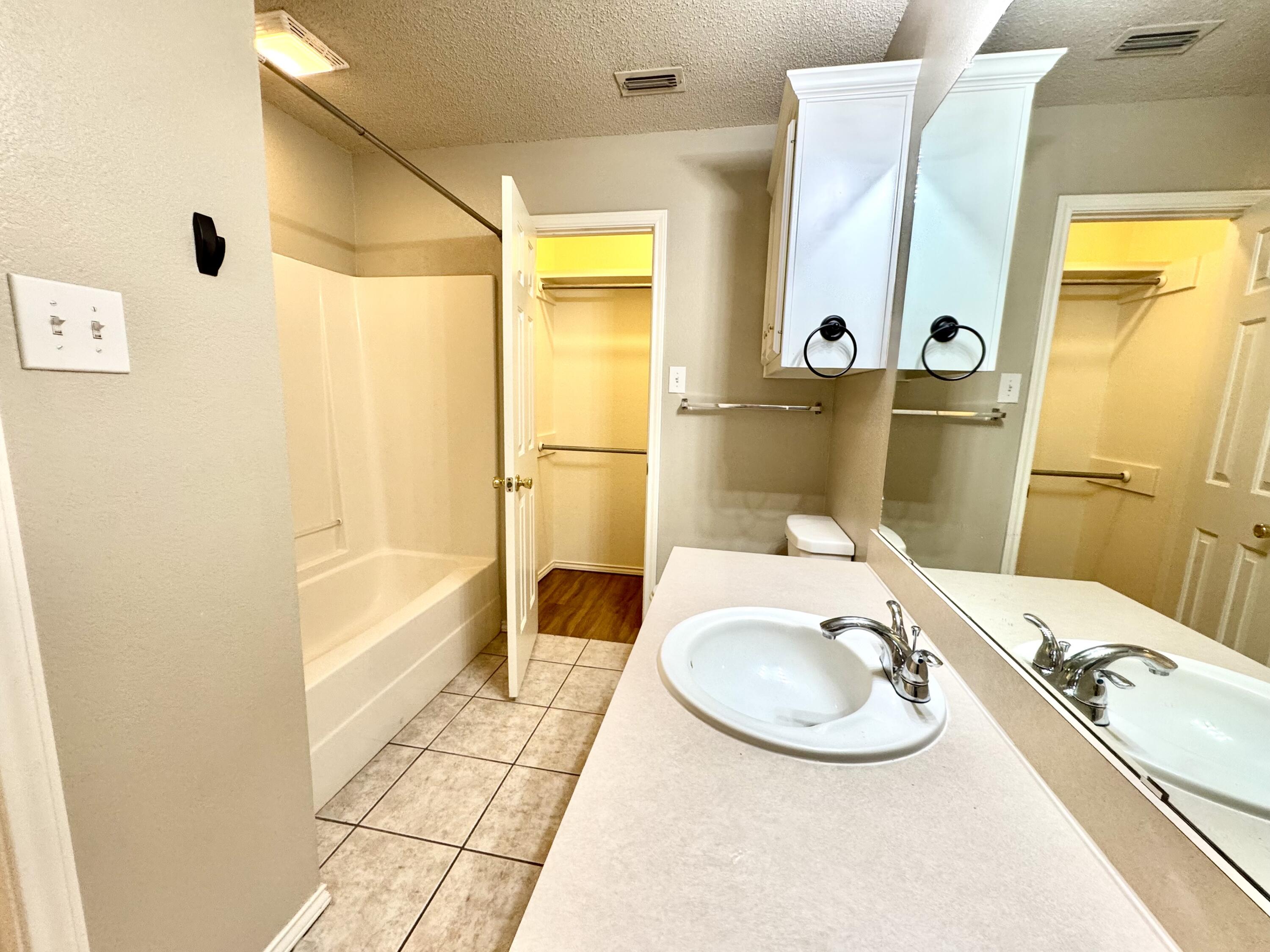 6536 7th Street Lubbock, TX 79416 - Photo 13 of 20 a bathroom with a sink and mirror with bathtub