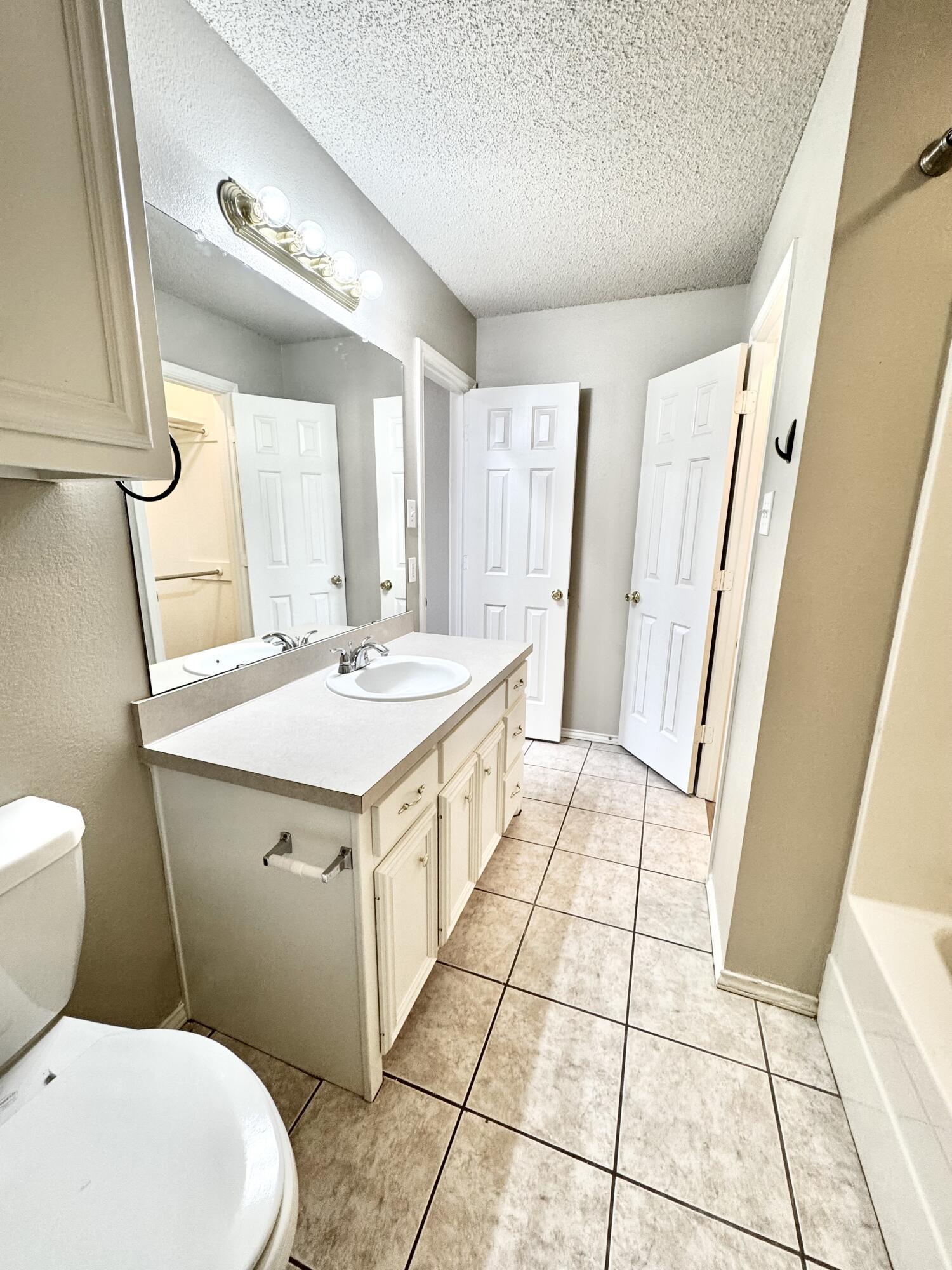 6536 7th Street Lubbock, TX 79416 - Photo 15 of 20 a bathroom with a sink a toilet and a mirror