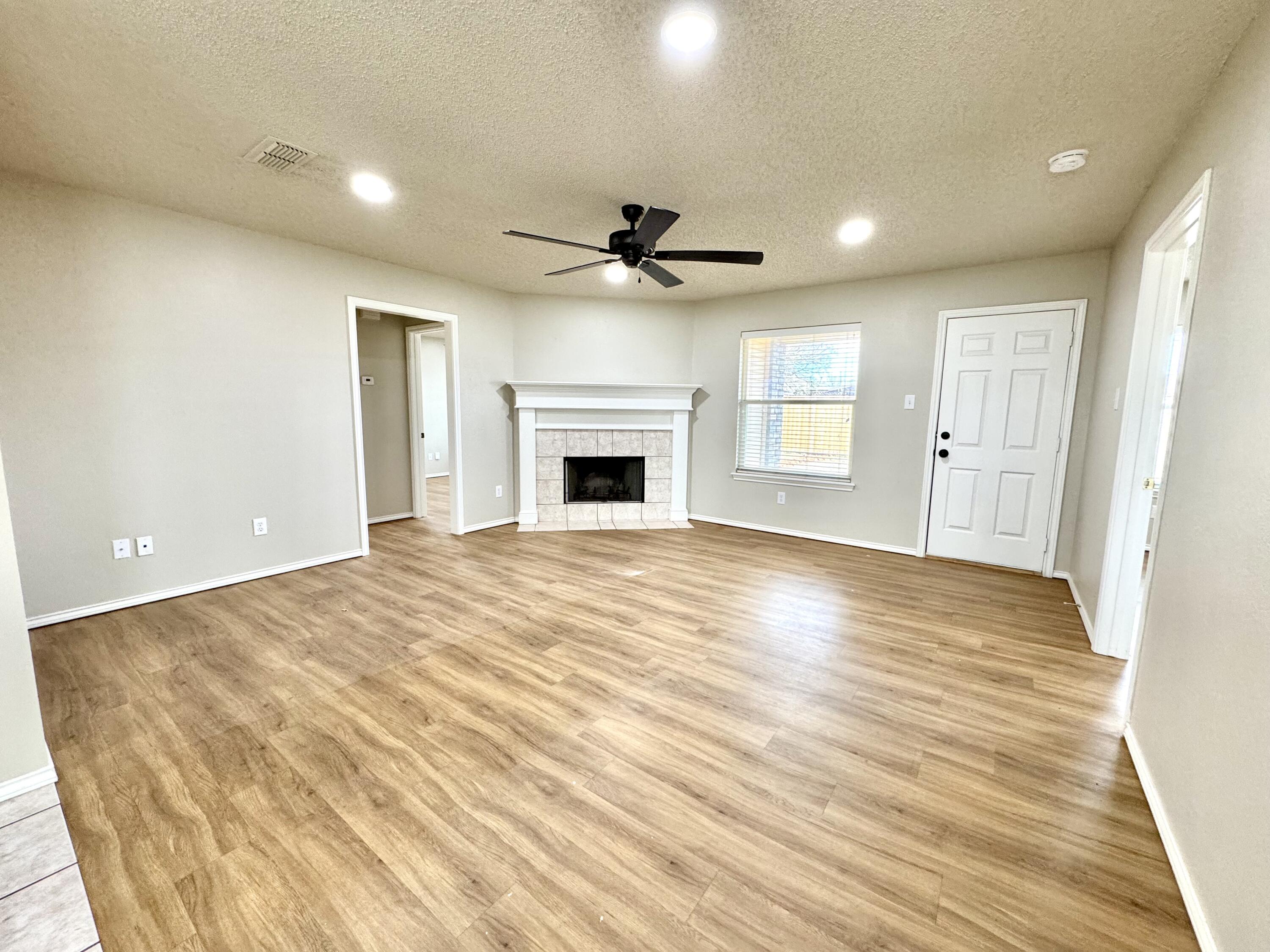6536 7th Street Lubbock, TX 79416 - Photo 3 of 20 an empty room with wooden floor fireplace and windows