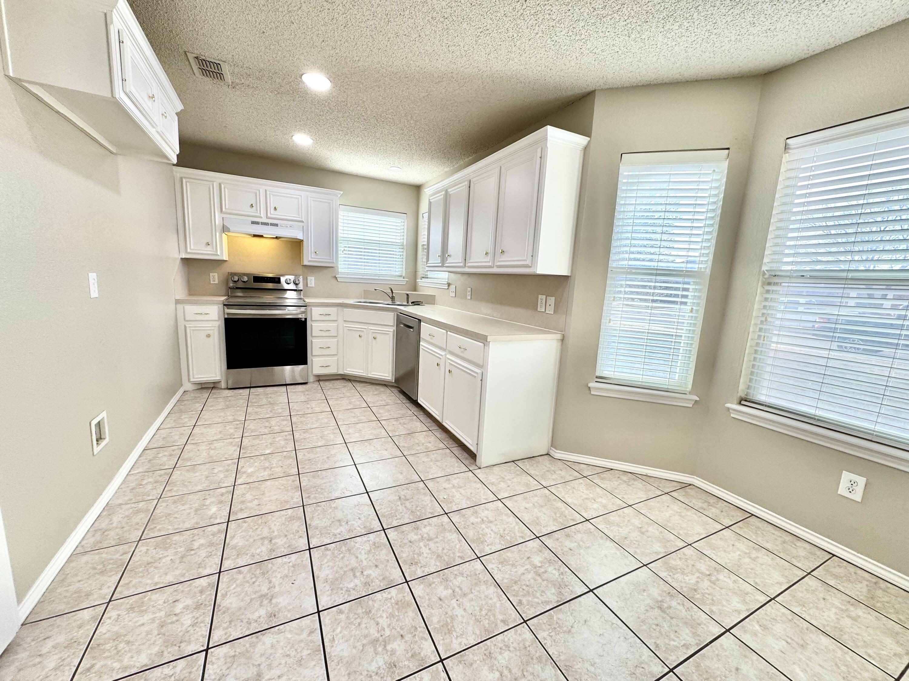 6536 7th Street Lubbock, TX 79416 - Photo 6 of 20 a kitchen with stainless steel appliances cabinets a sink and a stove top oven