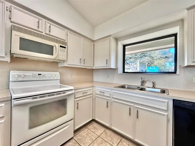 a kitchen with white cabinets stainless steel appliances and sink
