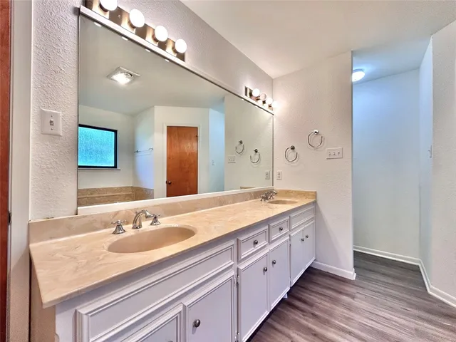 a bathroom with a granite countertop double vanity sink and mirror