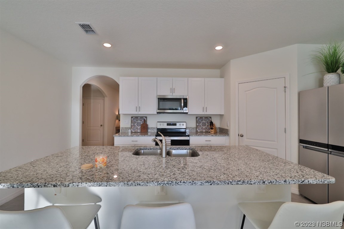 421 Anne Street DeLand, FL 32724 - Photo 6 of 44 a kitchen with stainless steel appliances granite countertop a sink a stove a refrigerator cabinets and chairs