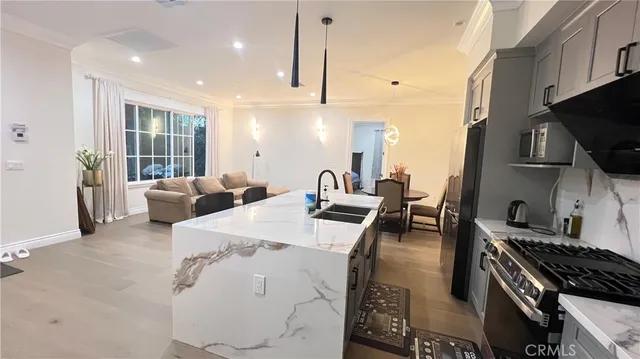 a open kitchen with stainless steel appliances kitchen island granite countertop a stove top oven a sink a dining table and chairs with wooden floor