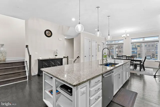 a kitchen with stainless steel appliances granite countertop a sink a center island a stove and a wooden floor