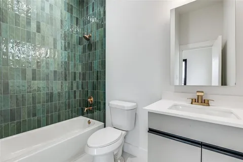 a bathroom with a bathtub shower sink mirror vanity and toilet