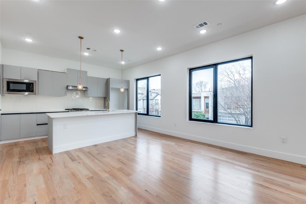2607 Calvin Street, Unit 3 Dallas, TX 75204 - Photo 5 of 26 a large kitchen with stainless steel appliances kitchen island a large counter top and a wooden floors
