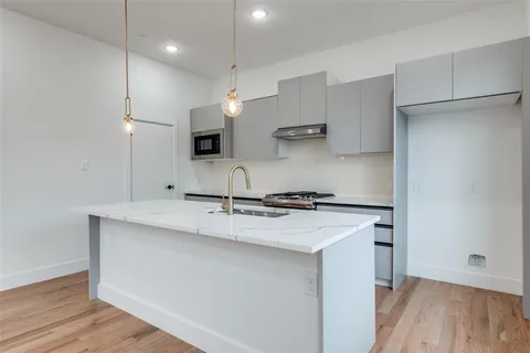 a kitchen with stainless steel appliances granite countertop a sink a stove a refrigerator and island with wooden floor