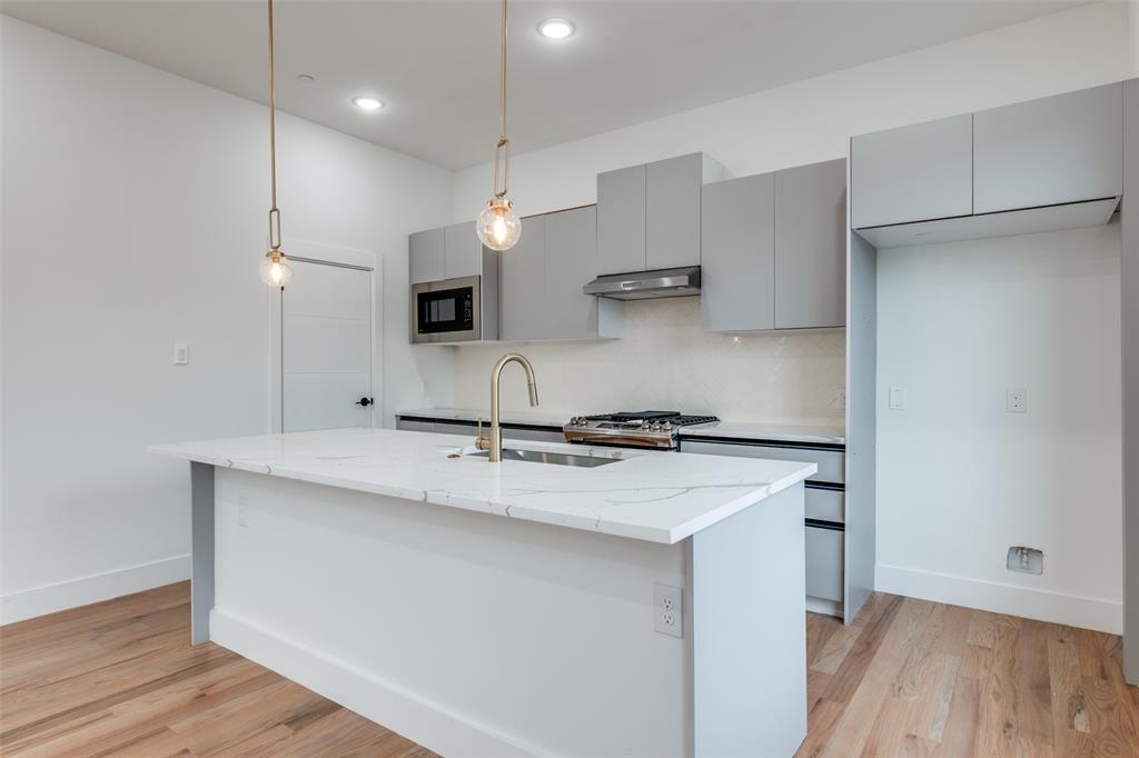 2607 Calvin Street, Unit 3 Dallas, TX 75204 - Photo 7 of 26 a kitchen with stainless steel appliances granite countertop a sink a stove a refrigerator and island with wooden floor