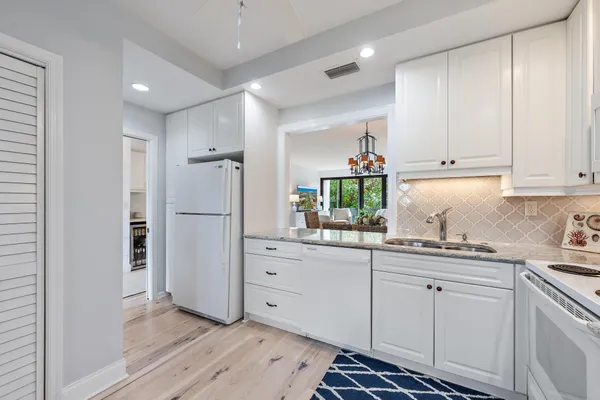 a kitchen with white cabinets and appliances