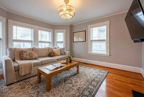 a living room with furniture a flat screen tv and a window