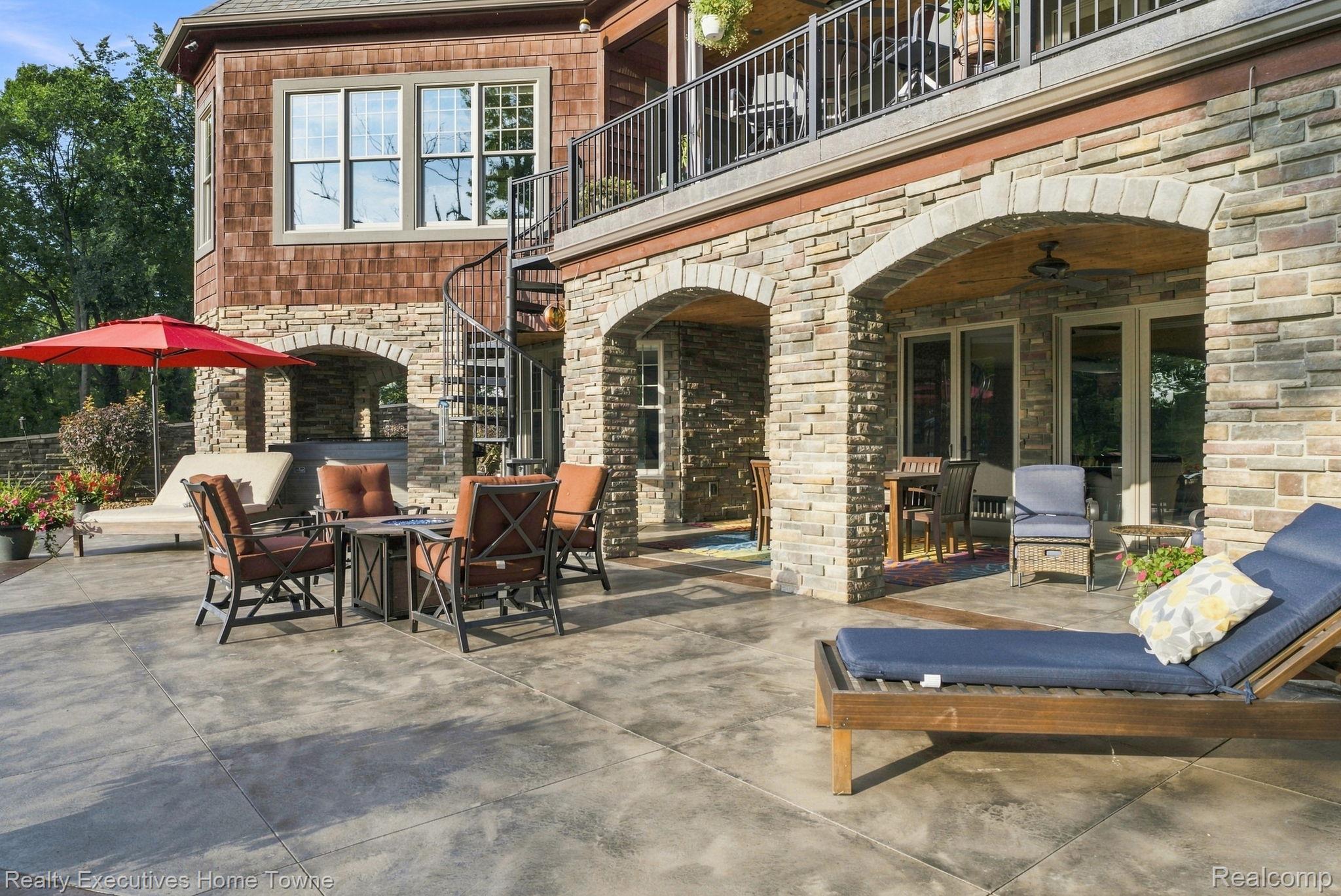 2829 Riverside Drive Port Huron, MI 48060 - Photo 61 of 99 Expansive concrete patio with stone-clad exterior, arched stone alcoves, spiral staircase, and an upper-level balcony with metal railing