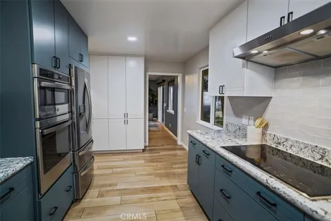 a kitchen with stainless steel appliances granite countertop a sink and wooden cabinets