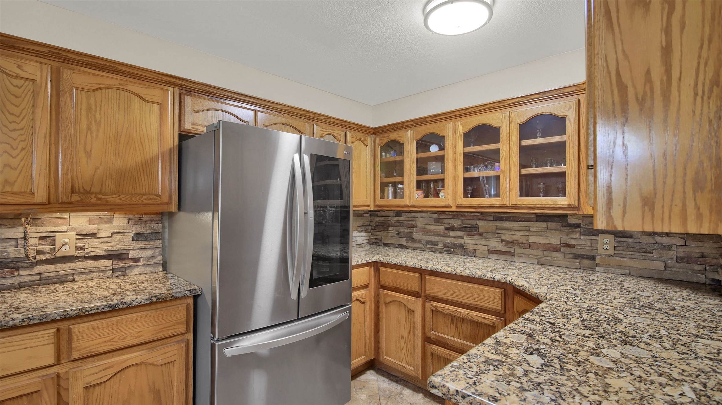 191 Jordan Lane Elgin, TX 78621 - Photo 8 of 29 Rich oak cabinetry pairs with granite countertops and a stone tile backsplash in this kitchen.