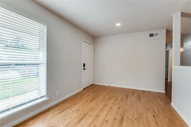 a view of empty room with wooden floor and fan