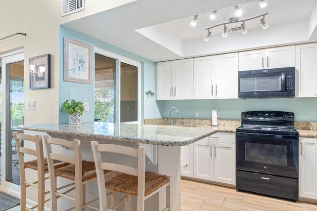 a kitchen with granite countertop a stove top oven microwave and cabinets