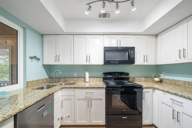 a kitchen with granite countertop a stove sink and cabinets