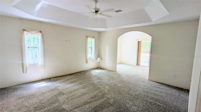 an empty room with windows and ceiling fan
