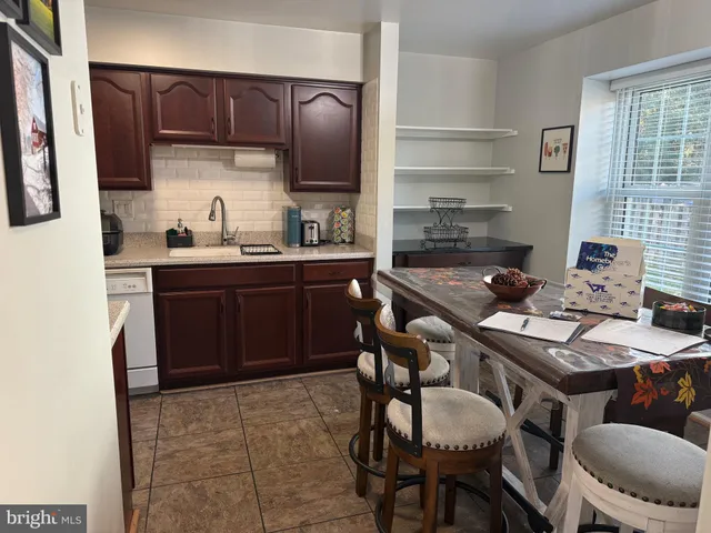 a kitchen with stainless steel appliances granite countertop a sink a stove a refrigerator a dining table and chairs