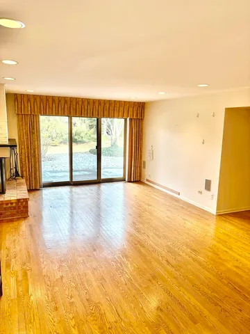 a view of empty room with wooden floor and fireplace
