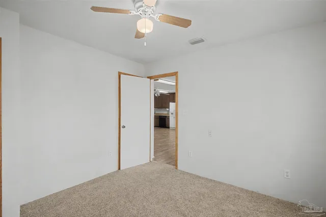 en empty room with a ceiling fan and a window