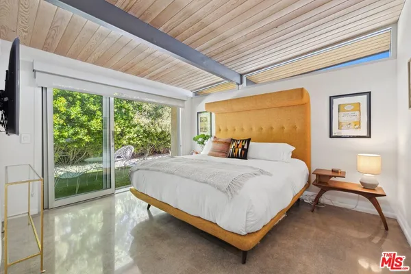 a bedroom with a bed a television and a large window