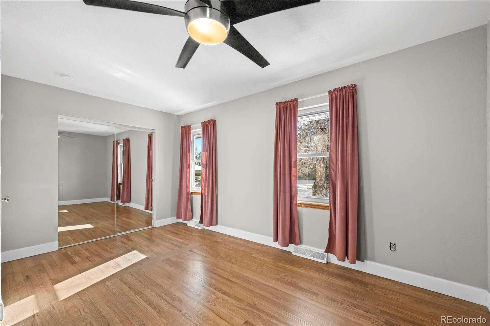 8213 Adams Way Denver, CO 80221 - Photo 11 of 22 a view of an empty room with window and wooden floor