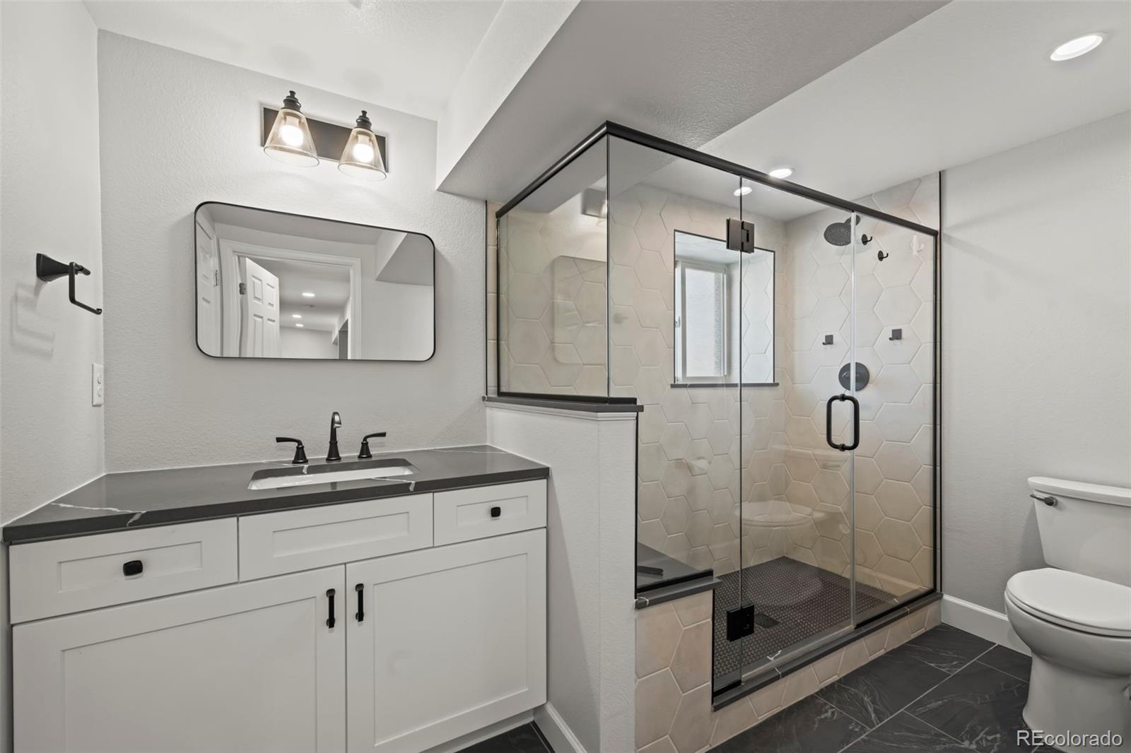 8213 Adams Way Denver, CO 80221 - Photo 15 of 22 a bathroom with a shower sink mirror and toilet