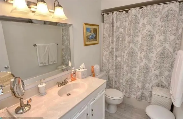 a bathroom with a sink a toilet and shower curtain