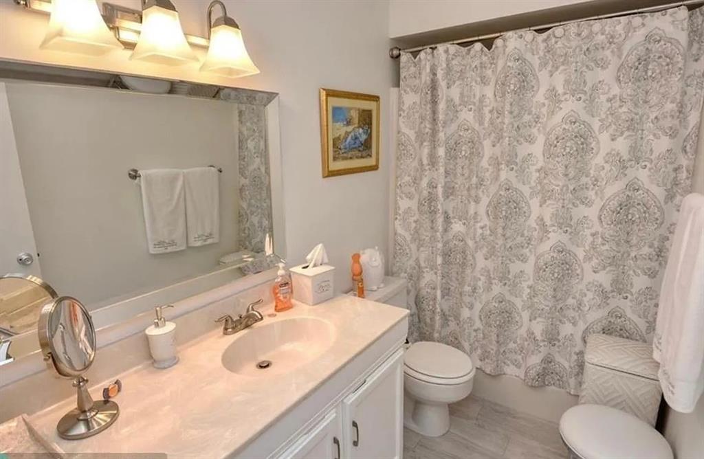 1225 Northwest 21st Street, Unit 3507 Stuart, FL 34994 - Photo 7 of 18 a bathroom with a sink a toilet and shower curtain