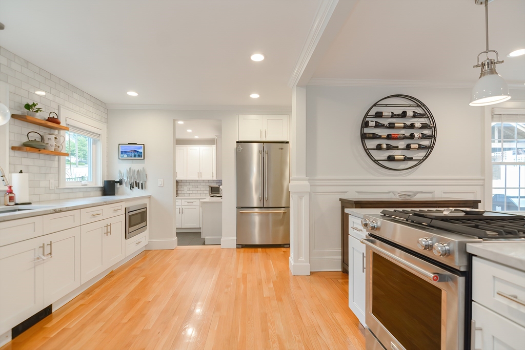 1133 Brook Road Milton, MA 02186 - Photo 19 of 40 a kitchen with granite countertop a stove top oven a sink dishwasher a refrigerator and a dining table with wooden floor