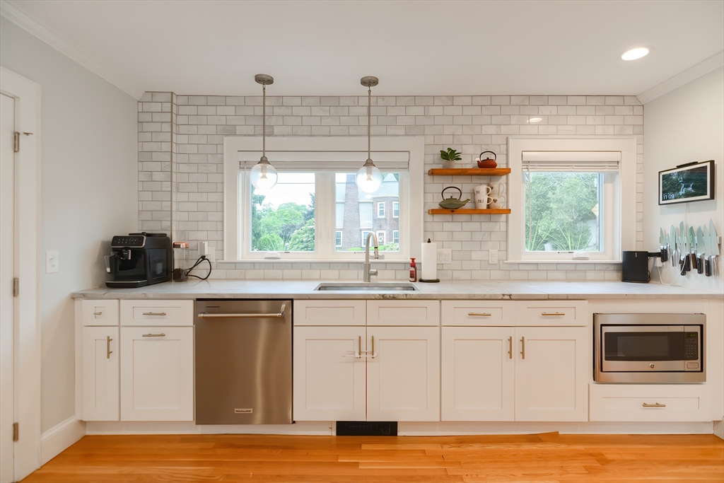 1133 Brook Road Milton, MA 02186 - Photo 22 of 40 a kitchen with kitchen island granite countertop a stove a sink and a microwave