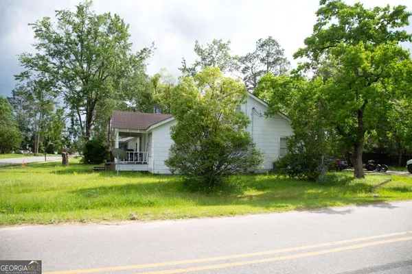 a front view of a house with a garden and trees