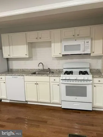 a kitchen with granite countertop white cabinets and a stove