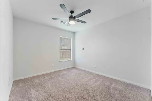 an empty room with ceiling fan and window