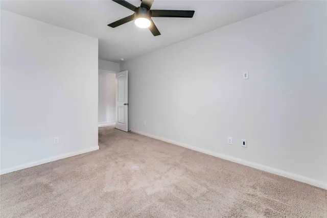 an empty room with a ceiling fan and window