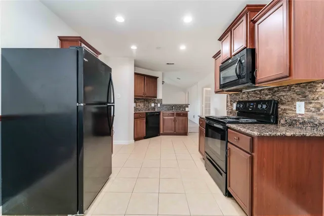 a large kitchen with stainless steel appliances granite countertop a refrigerator and a stove top oven