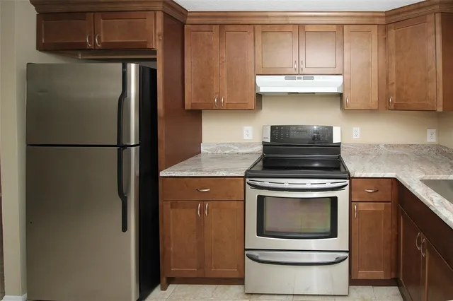 a kitchen with granite countertop a sink cabinets and stainless steel appliances