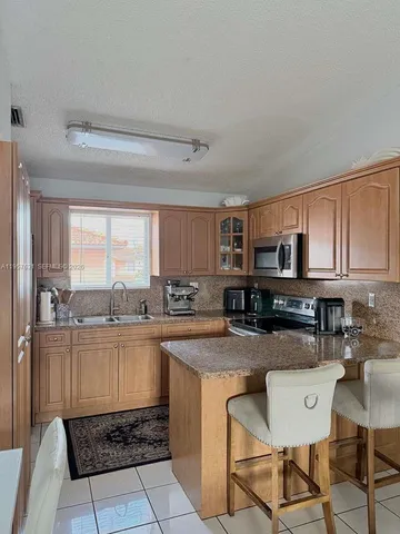 a kitchen with kitchen island granite countertop a table chairs microwave and cabinets
