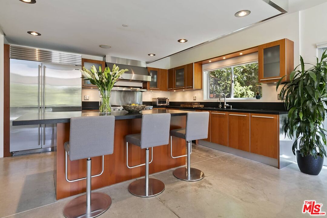12310 Rochedale Lane Los Angeles, CA 90049 - Photo 18 of 53 a kitchen with stainless steel appliances granite countertop table chairs sink and cabinets