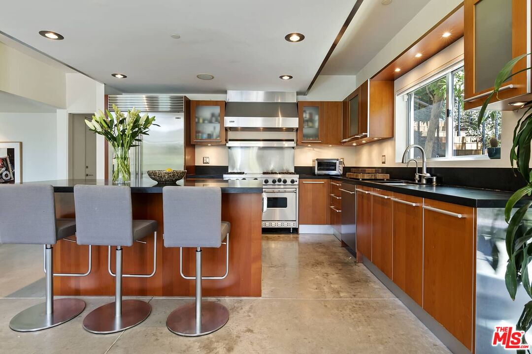 12310 Rochedale Lane Los Angeles, CA 90049 - Photo 19 of 53 a kitchen with stainless steel appliances granite countertop a stove top oven a sink a dining table and chairs