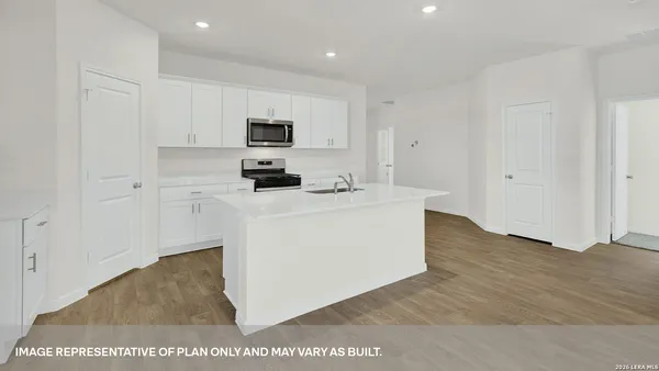 a kitchen with stainless steel appliances a sink a stove a microwave a refrigerator a white cabinets and wooden floor