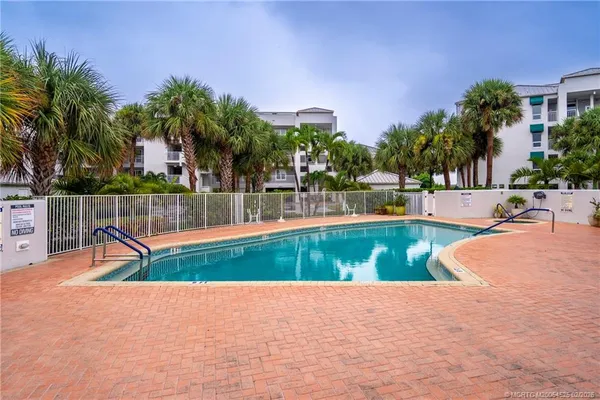 a view of swimming pool with a yard and palm trees