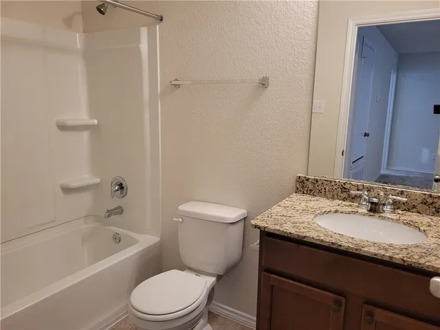 a bathroom with a granite countertop sink a toilet and shower