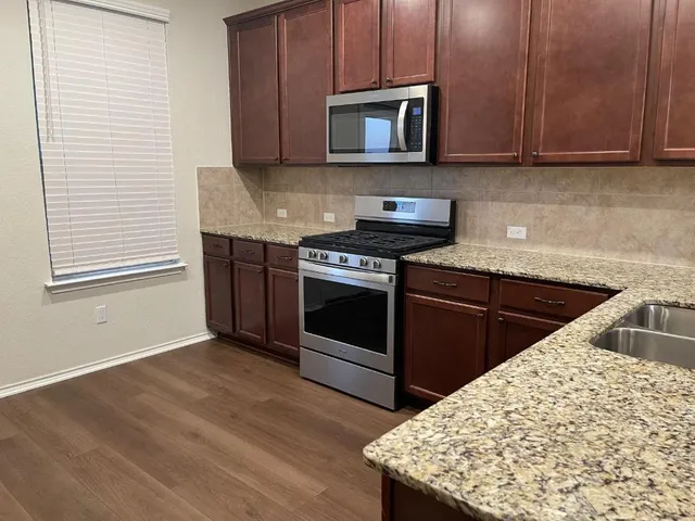 a kitchen with stainless steel appliances granite countertop a stove a sink and a microwave